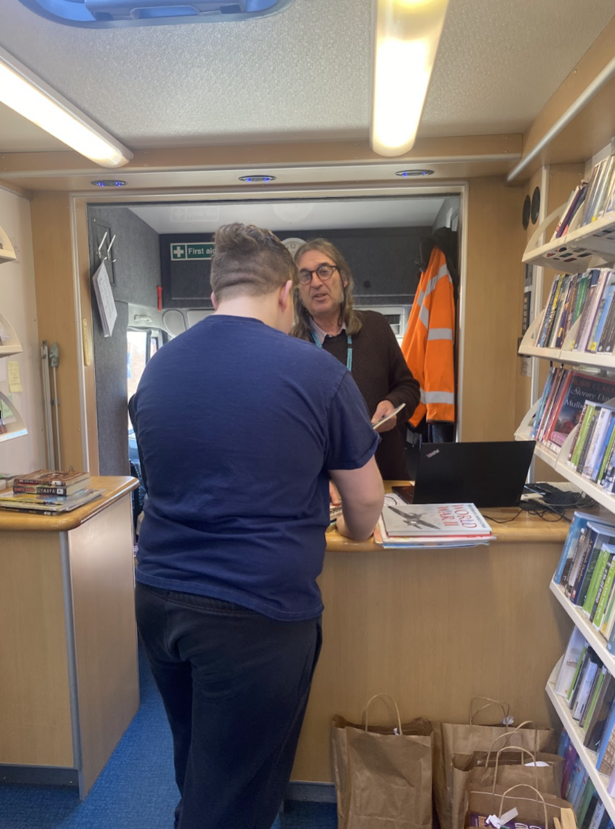 A student booking a book out at the counter of the library bus
