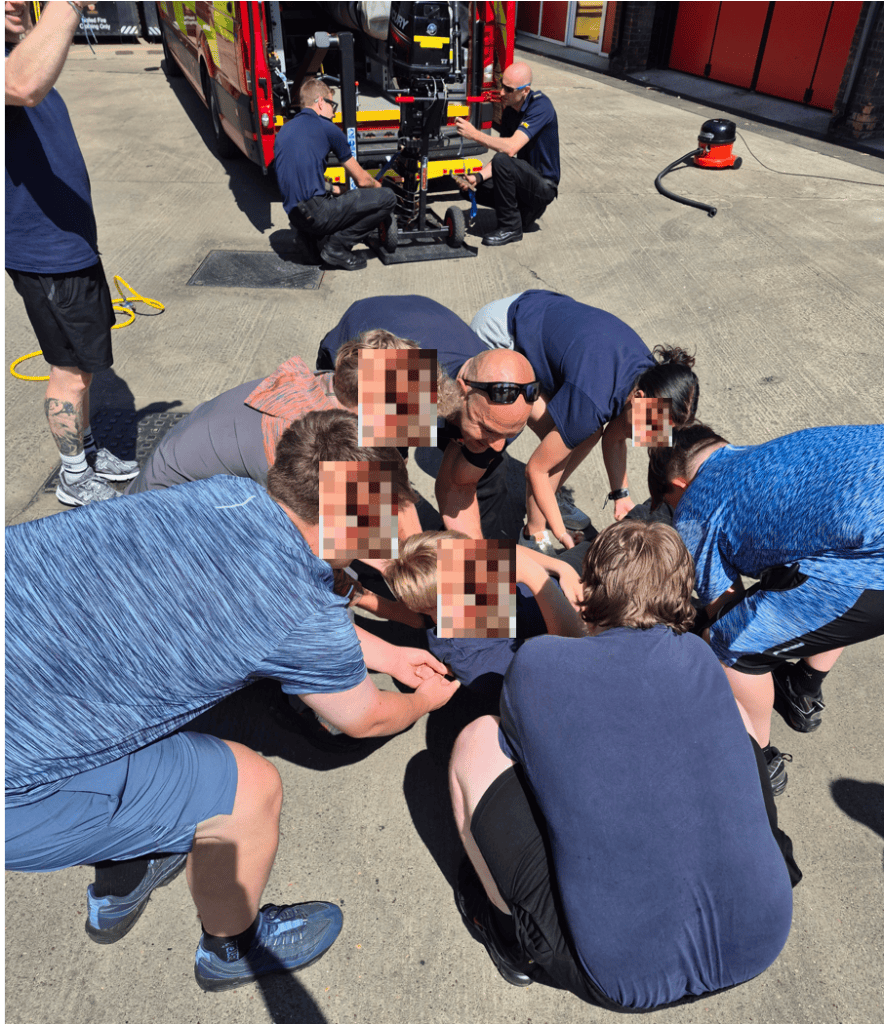 Students practising a rescue technique with fire officers at the fire station