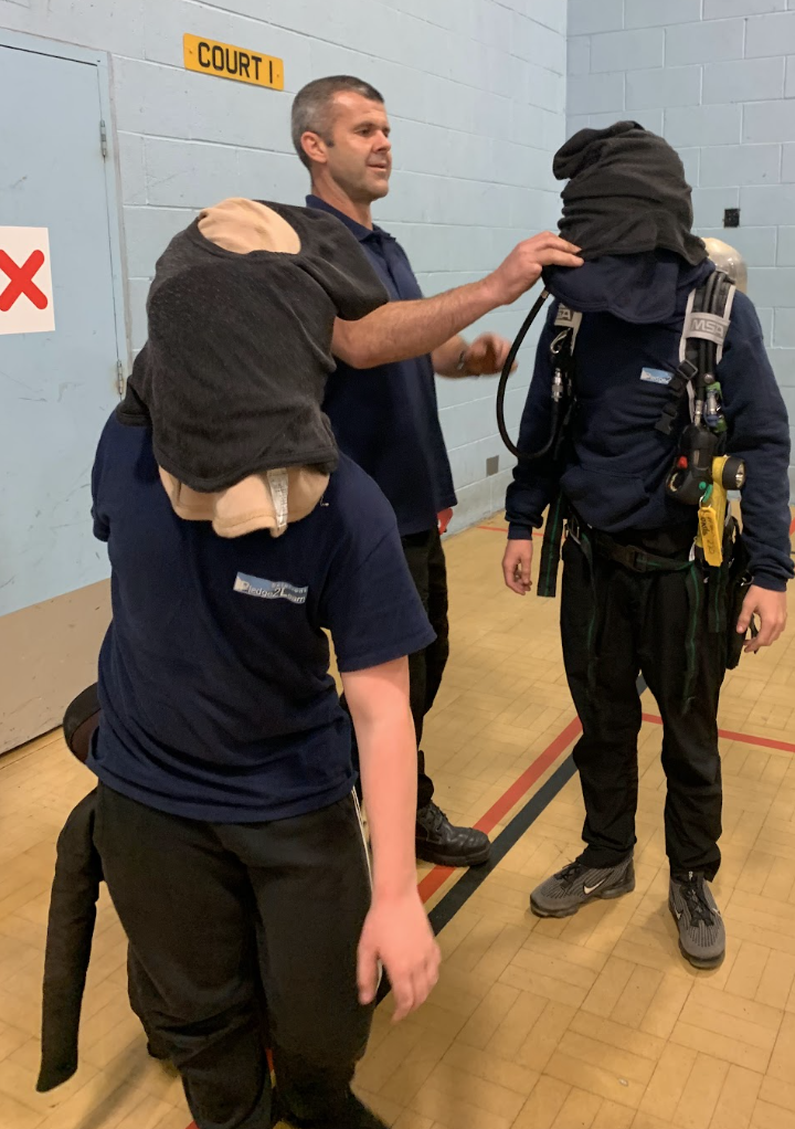 A student wearing a blindfold working through a simulated smoke-filled room