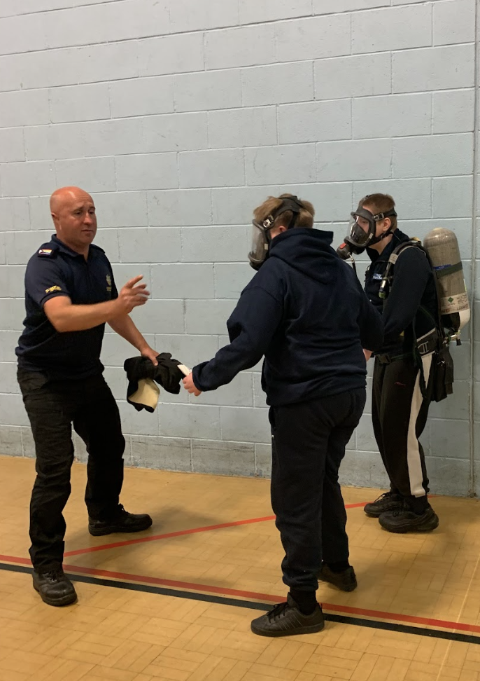 Students wearing breathing apparatus air tanks over firefighter tunics