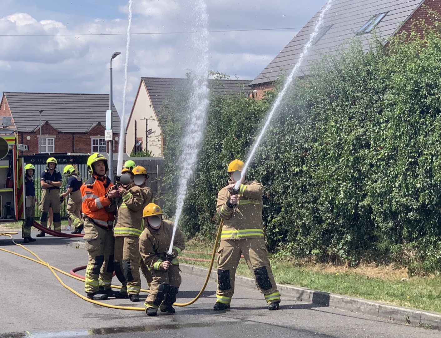 Students holding a charged fire hose alongside firefighters